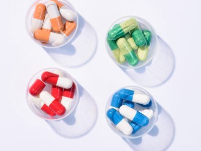 top view of various colorful pills in plastic cans on white