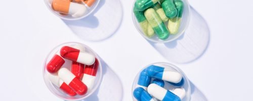 top view of various colorful pills in plastic cans on white